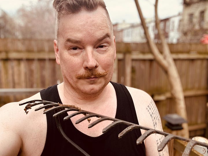Getting sweaty in the backyard in a black tank top and a metal rake.