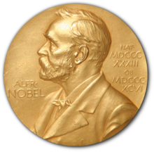 A golden medallion with an embossed image of Alfred Nobel facing left in profile. To the left of the man is the text "ALFR•" then "NOBEL", and on the right, the text (smaller) "NAT•" then "MDCCCXXXIII" above, followed by (smaller) "OB•" then "MDCCCXCVI" below. A golden medallion with an embossed image of Alfred Nobel facing left in profile. To the left of the man is the text "ALFR•" then "NOBEL", and on the right, the text (smaller) "NAT•" then "MDCCCXXXIII" above, followed by (smaller) "OB•" then "MDCCCXCVI" below.