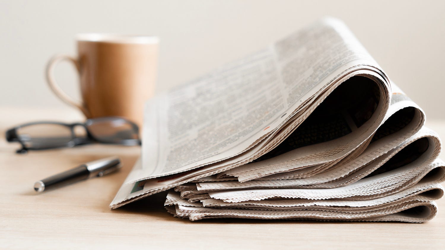 Photo of a desktop with coffee cup and morning paper.
