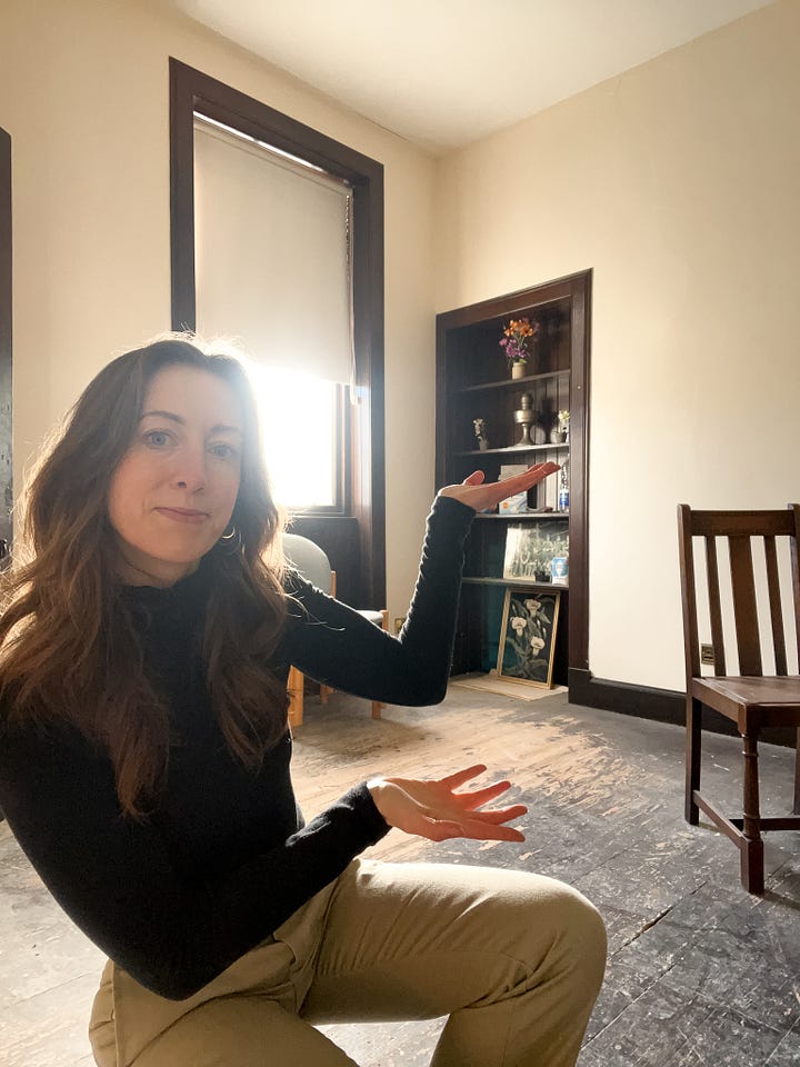 On the left, beams of light from the window fall on a dusty wooden floor. On the right, Christina holds her arms up to show one of the library rooms with wood floors, cream walls and an alcove of dark brown shelves.