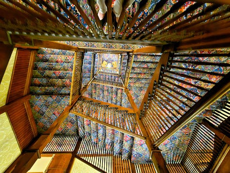 The historic central staircase at Mohonk with wooden spindles and colorful carpet.