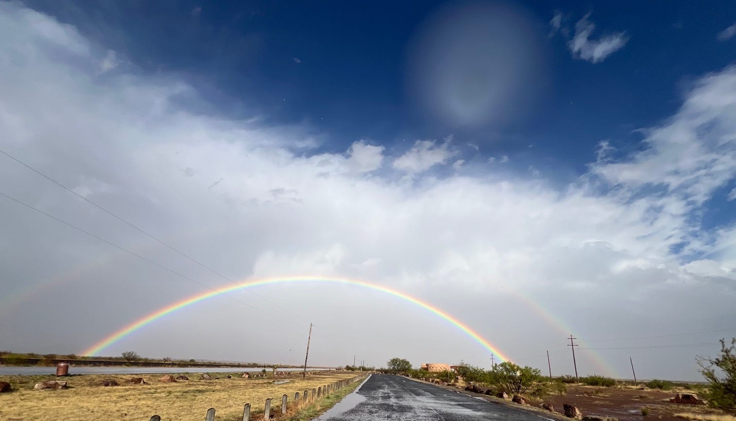 A rainbow over a road

Description automatically generated