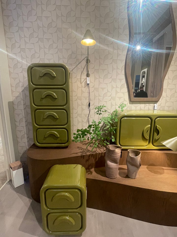 Open shelving display at Maison & Objet Paris 2026 featuring warm wood cabinetry, sculptural ceramics, decorative vessels, and earthy lifestyle accessories. Green lacquered storage furniture vignette at Maison & Objet Paris 2026 with rounded forms, modular cabinets, natural wood surfaces, and soft neutral wall textures.