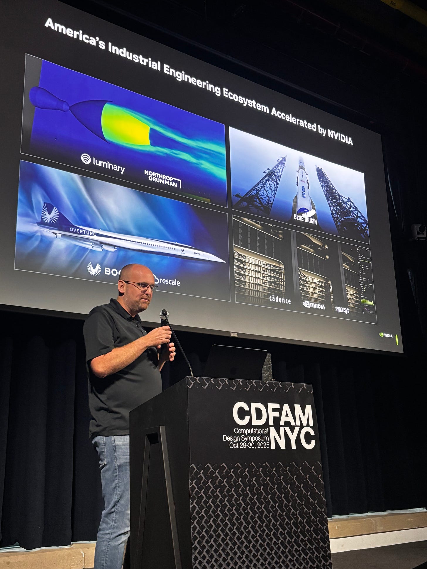 A speaker presenting at the CDFAM NYC 2025 Computational Design Symposium, with a displayed presentation slide featuring images related to the industrial engineering ecosystem, including various vehicles and technologies from companies like Northrop Grumman and Blue Origin.