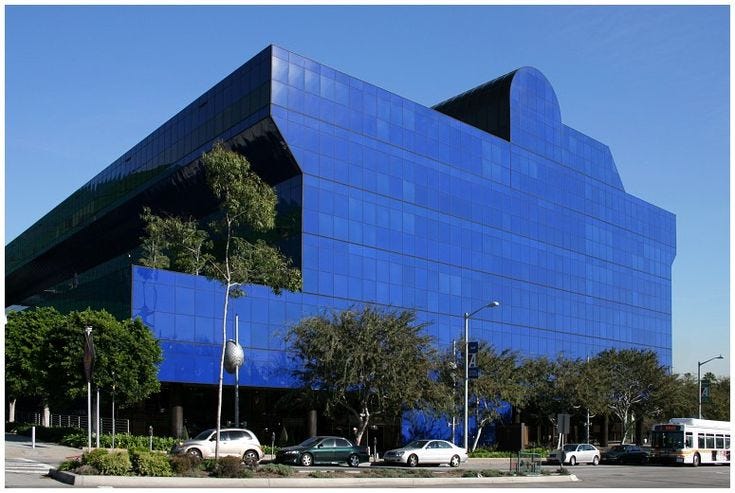 This may contain: a large blue building with cars parked in front