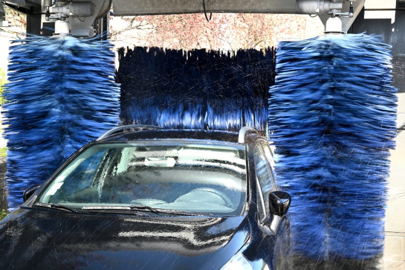 car going through a car wash with big blue brushes
