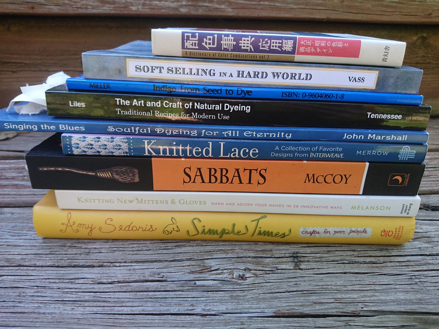 9 books stacked on top of each other on a wooden deck stair