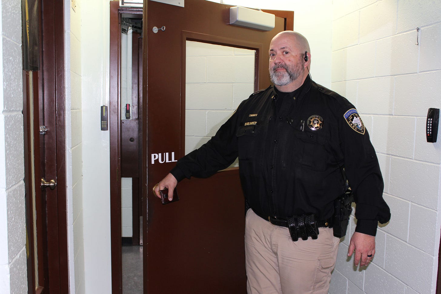 A police officer opens a door that leads to a hallway in a prison. A police officer opens a door that leads to a hallway in a prison.