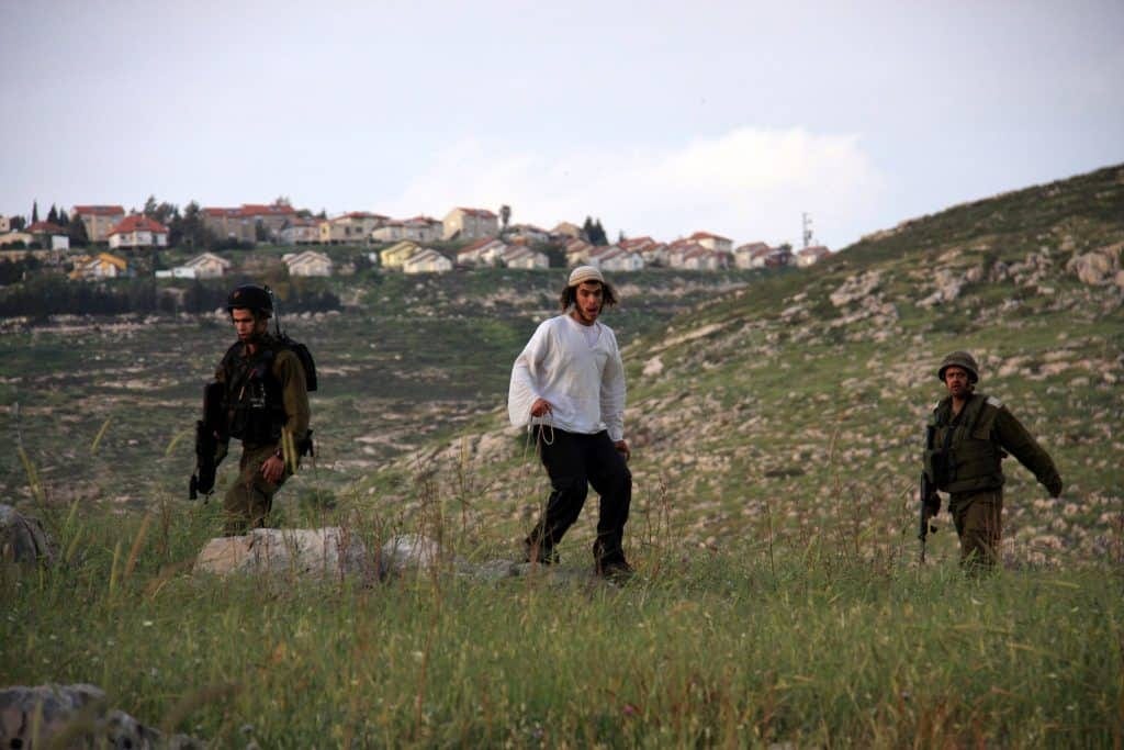 Settler from the Har Bracha settlement throws stones at Palestinian villagers from Burin under protection of the Israeli army, April 19, 2011.(Photo: Wagdi Eshtayah/APA Images)