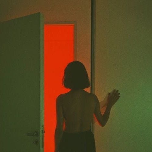 This may contain: a woman standing in front of a red door with her hands out to the side
