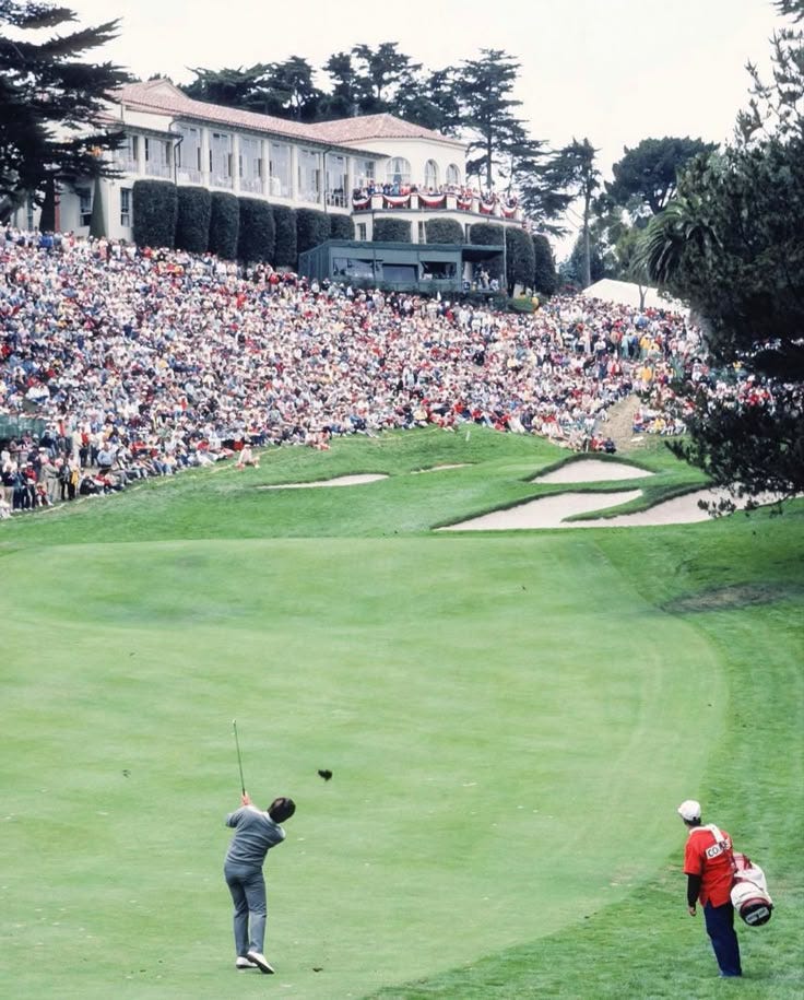 This may contain: two people playing golf in front of a large crowd at a golf course with spectators