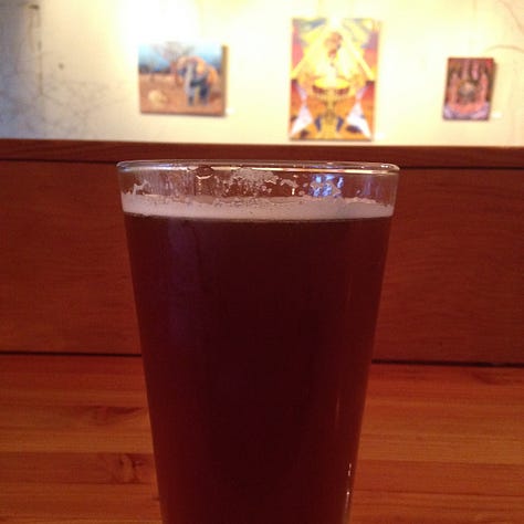 A person sitting cross legged, a sidewalk with strewn flower petals, a glass of beer.