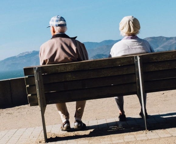 man and woman sitting on bench facing sea man and woman sitting on bench facing sea