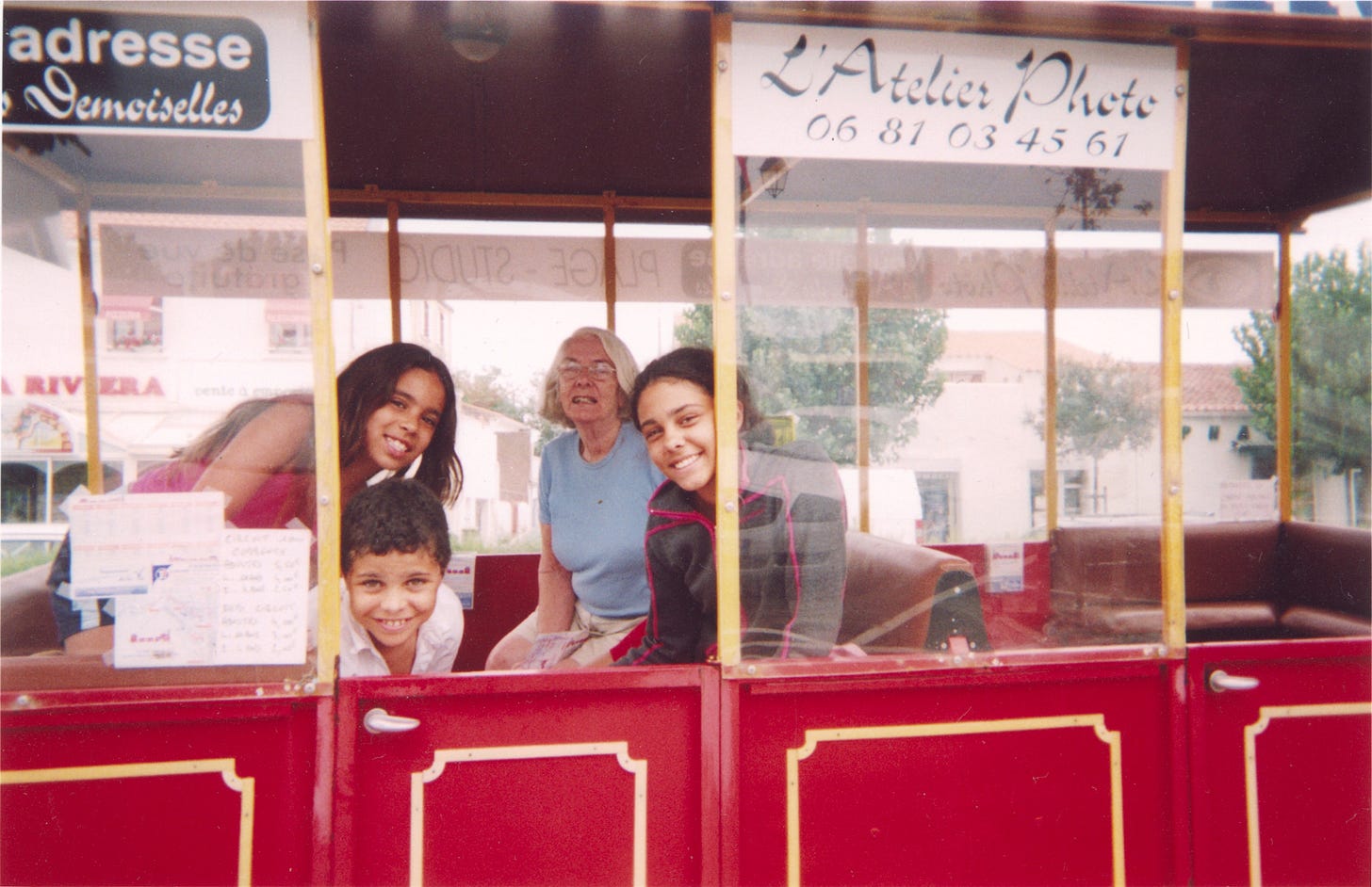 Three children and a woman on a toy train smiling