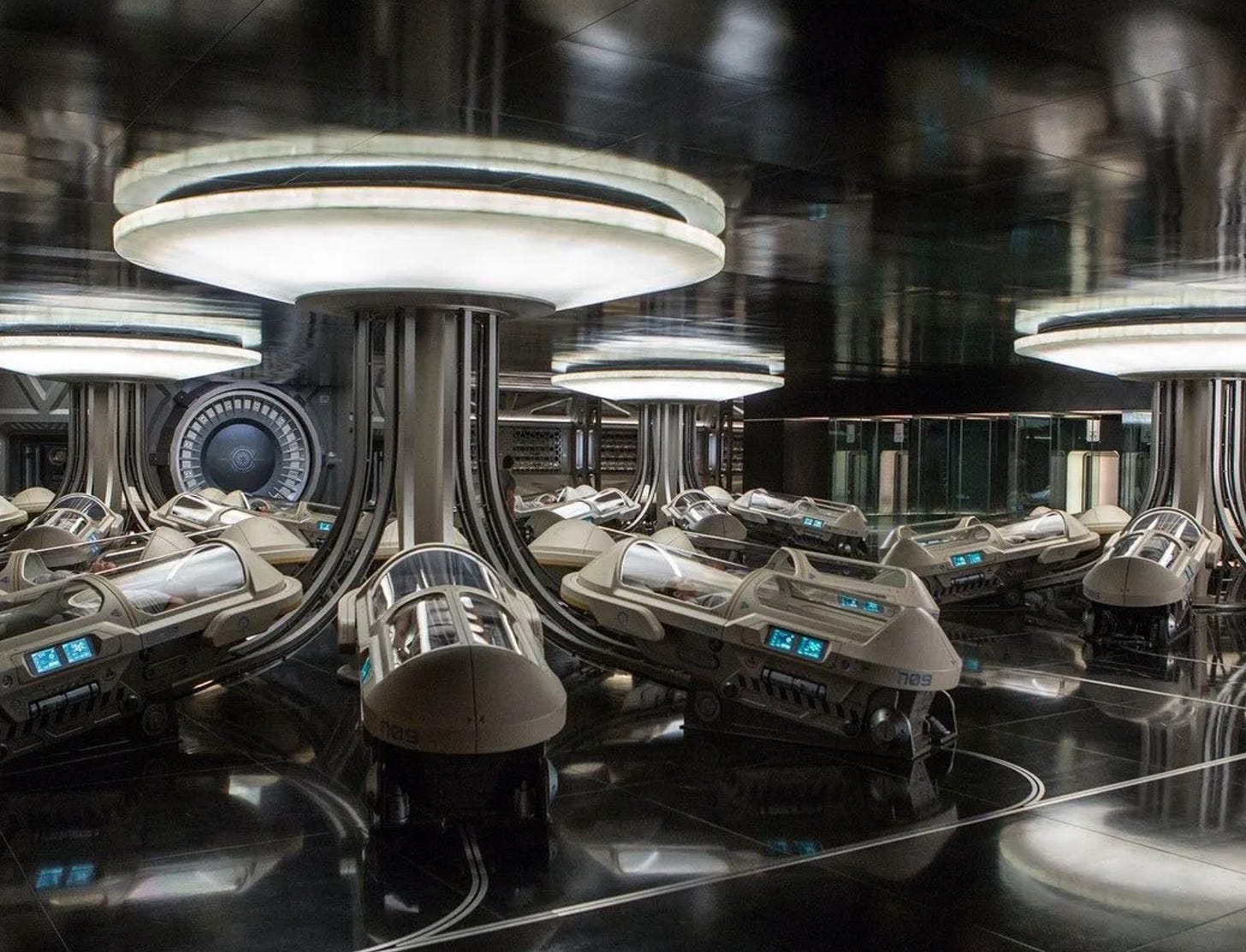 A reflective room filled with bright lights and enclosed sleep pods.