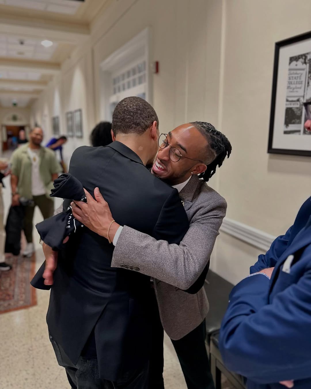 D'Shawn Doughty hugs another man in a hallway as onlookers watch