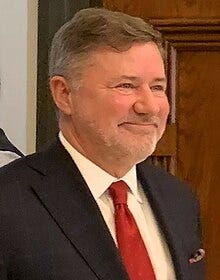 A person in a suit and tie
Description automatically generated A person in a suit and tie
Description automatically generated