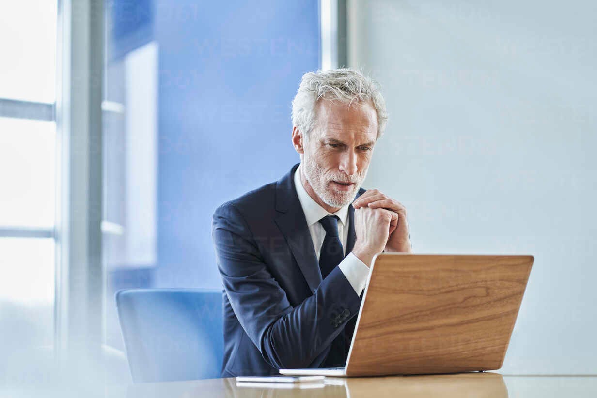 Focused businessman using laptop at desk in office stock photo
