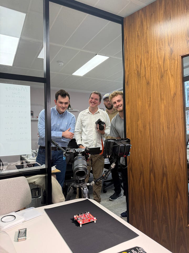 Four men smiling at the camera with a red computer chip on the table in front of them (left hand side), three men sat down on chairs while one speaks in front of a whiteboard (right hand side)