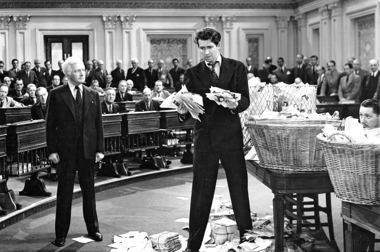 Jimmy Stewart as Jefferson Smith during the Senate filibuster scene in Mr. Smith Goes to Washington, standing amid overflowing baskets of letters from citizens, representing democratic participation and moral endurance.