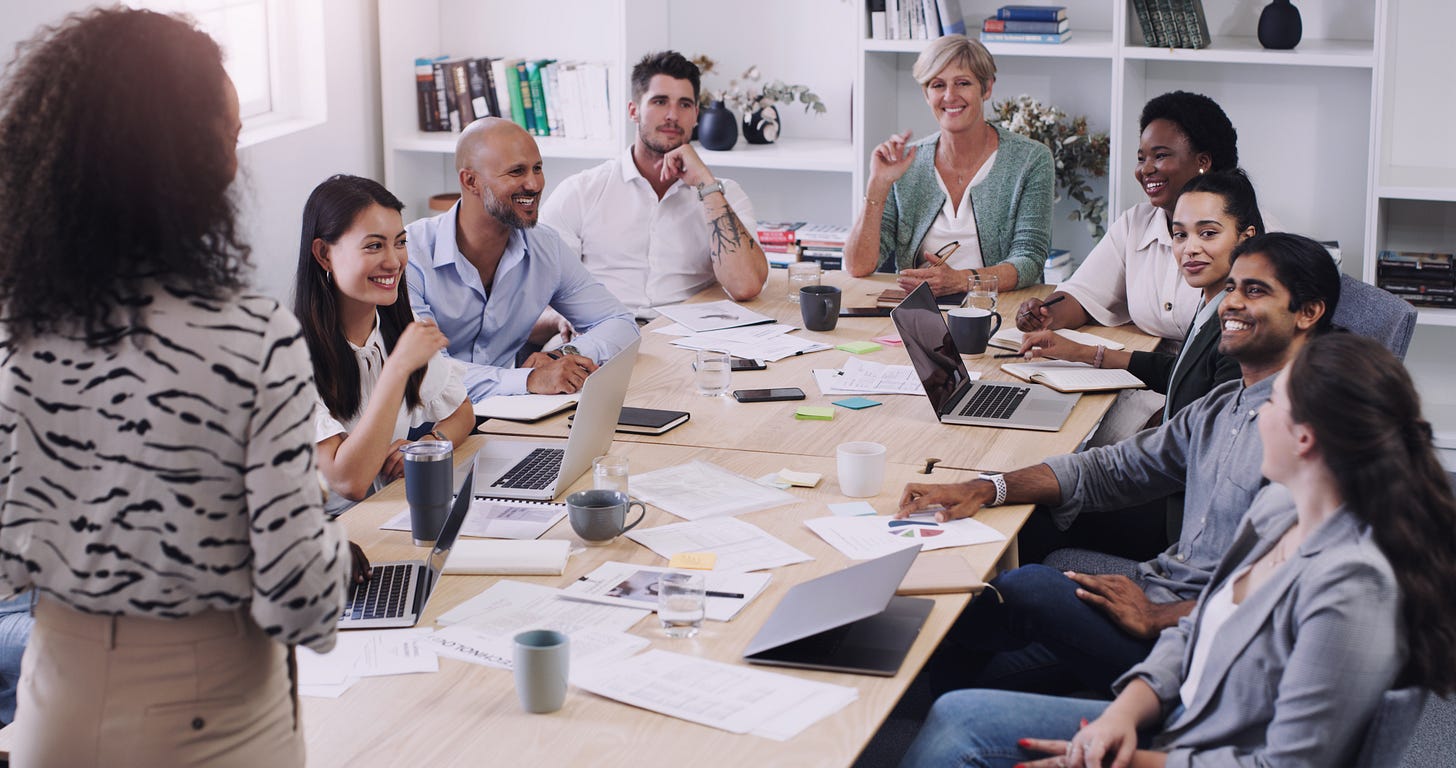 A diverse group of people sitting at a conference room table having a conversation. 