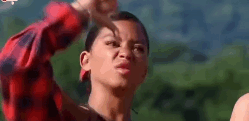 a woman is making a funny face with her hand in her face .
