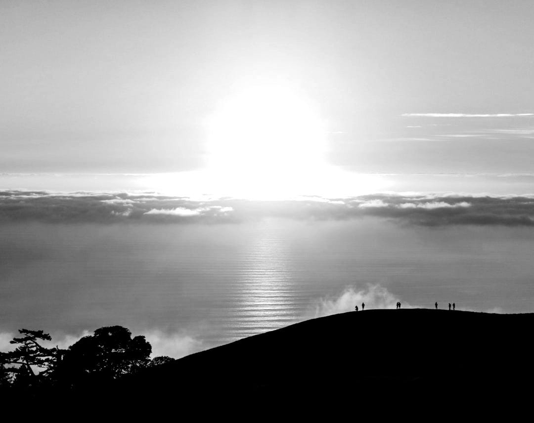 people on top of hill under white clouds golden hour photography