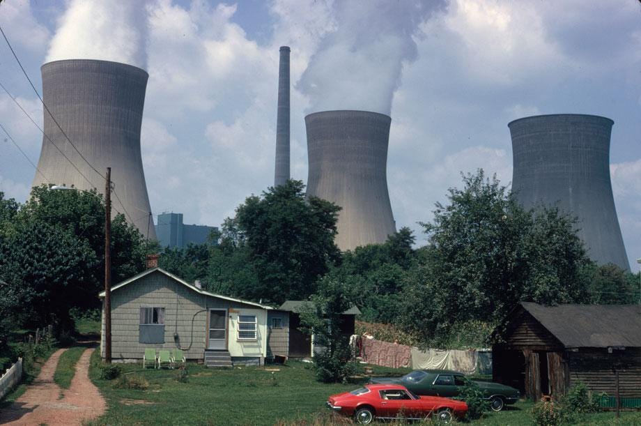 Water cooling towers of the John Amos Power Plant loom over Poca, WV, home that is on the other side of the Kanawha River. Two of the towers emit great clouds of steam.” Harry Schaefer, Poca, West Virginia, August 1973 Water cooling towers of the John Amos Power Plant loom over Poca, WV, home that is on the other side of the Kanawha River. Two of the towers emit great clouds of steam.” Harry Schaefer, Poca, West Virginia, August 1973