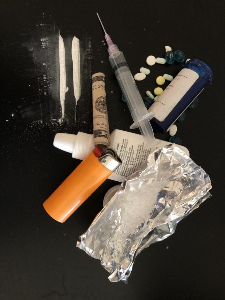 A variety of drugs and paraphernalia,including a syringe, lighter, lines of cocaine, a rolled up dollar bill, and a drug spray bottle. A variety of drugs and paraphernalia,including a syringe, lighter, lines of cocaine, a rolled up dollar bill, and a drug spray bottle.