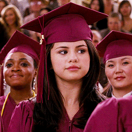 This may contain: a group of women in graduation caps and gowns are looking at the camera with many people behind them