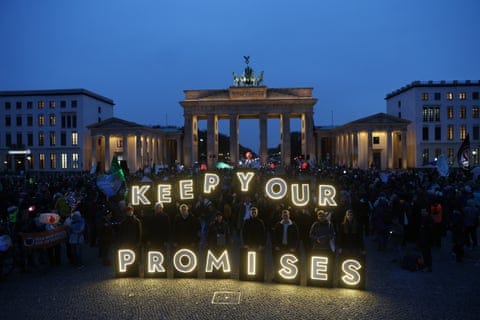 People behind illuminated letters spelling ‘keep your promises’