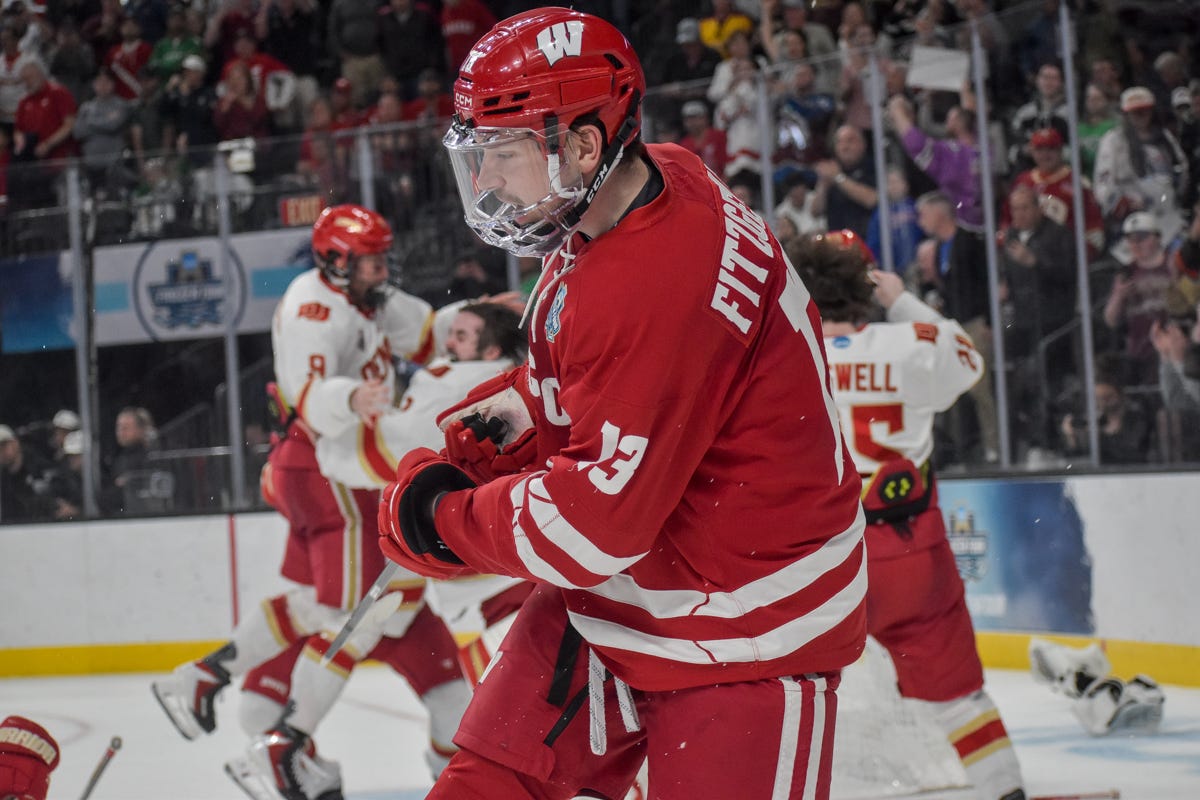 2026 Mens Frozen Four celebration. Christian Fitzgerald skates past Denver Pioneers hockey team with head down. 2026 Mens Frozen Four celebration. Christian Fitzgerald skates past Denver Pioneers hockey team with head down.