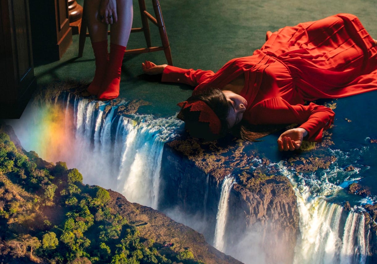 Red Velvet member Joy dressed in red laying on a green carpet that becomes a waterfall.