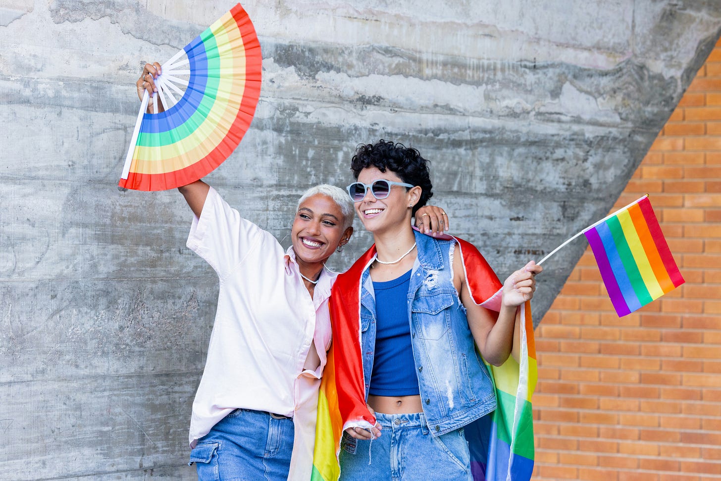 two humans waving pride flags two humans waving pride flags