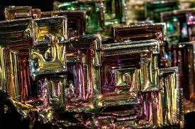 Two images of the metal bismuth, which has a multicolored iridescence and geometric structure.