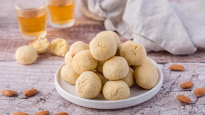 Delicate almond biscuits. One plate with natural ones, one plate of lightly coloured pastel, pink, green & brown
