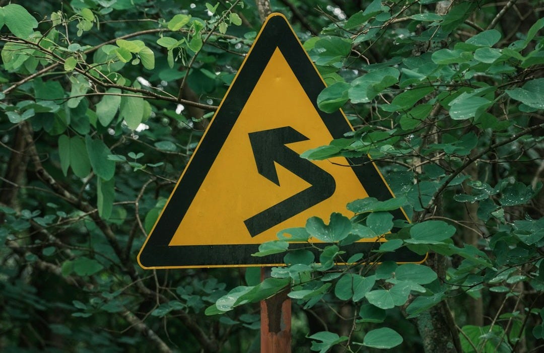 Yellow warning sign with winding road symbol