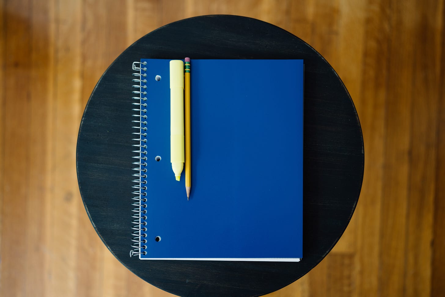An arrangement of a spiral notebook, a pencil, and a highlighter. An arrangement of a spiral notebook, a pencil, and a highlighter.