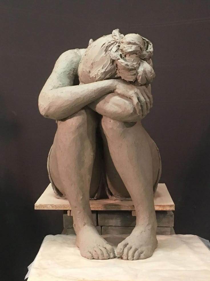 This may contain: a statue of a man sitting on top of a wooden block with his arms crossed