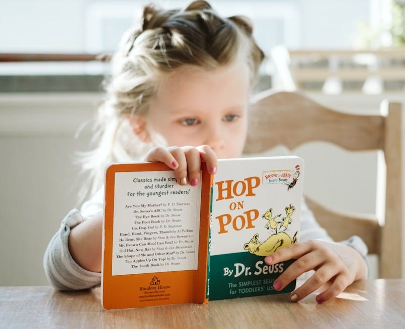 girl sitting while reading book