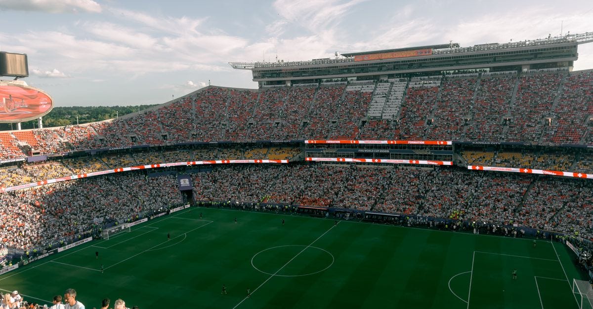 Photo: Allen Boguslavsky / Pexels Aerial view of a lively soccer match in a bustling outdoor stadium filled with enthusiastic fans.