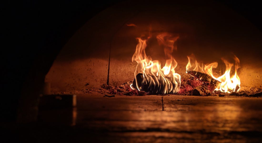A close-up of a woodburning oven with a fire lit A close-up of a woodburning oven with a fire lit