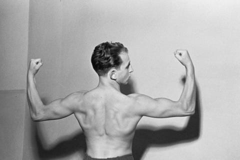 Portrait of a boxer showing his upper body muscles, shot from behind.