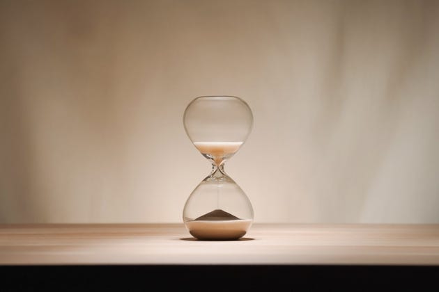 Minimalist Glass time almost over Hourglass on Wooden Surface with Beige Background toplit Minimalist Glass time almost over Hourglass on Wooden Surface with Beige Background toplit
