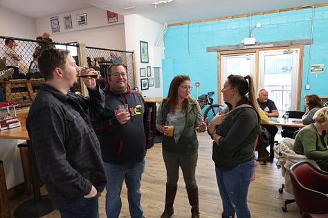 People drinking beer sitting down and standing up with frogs and toads in the background