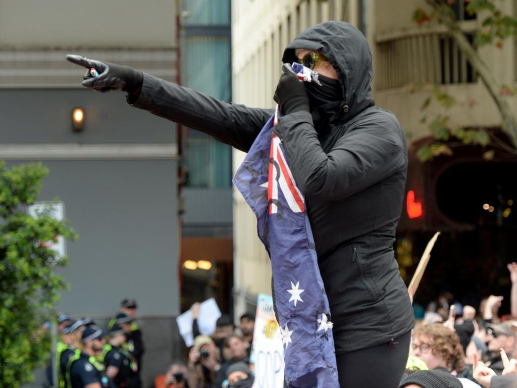 A demonstrator sets fire to an Australian flag at a pro-trans rally outside Parliament House. Picture: Andrew Henshaw