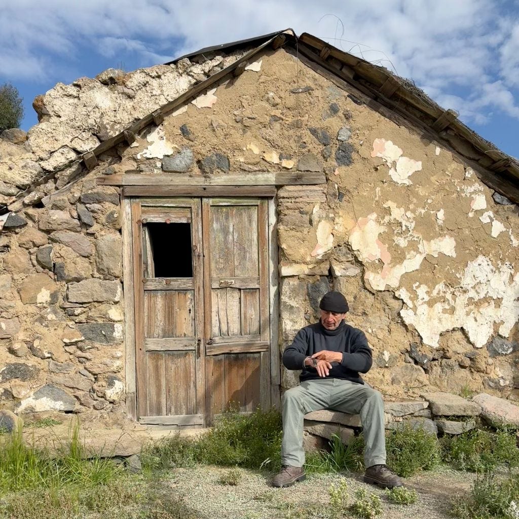 Old man sitting in front of ancient stone hut in the ghost village of Pampa de Arrieros, Peru