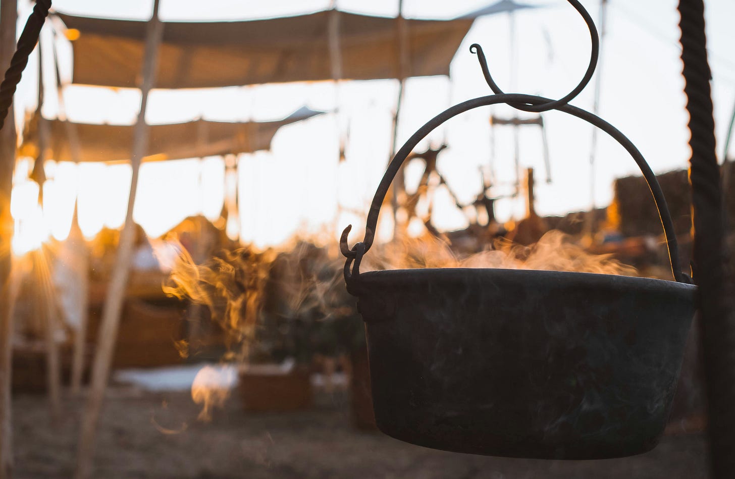 Steaming cauldron against a blurred tent camp background