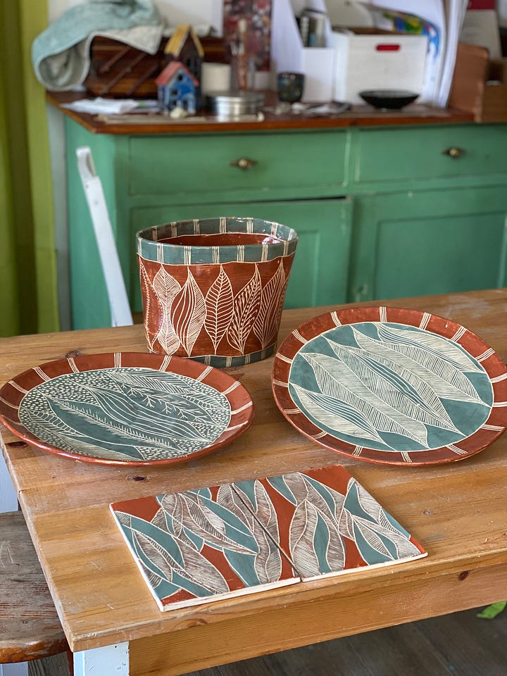 ceramic pieces decorated with a nature abstract design using slips and sgraffito: two platters, two flat panels and a vase