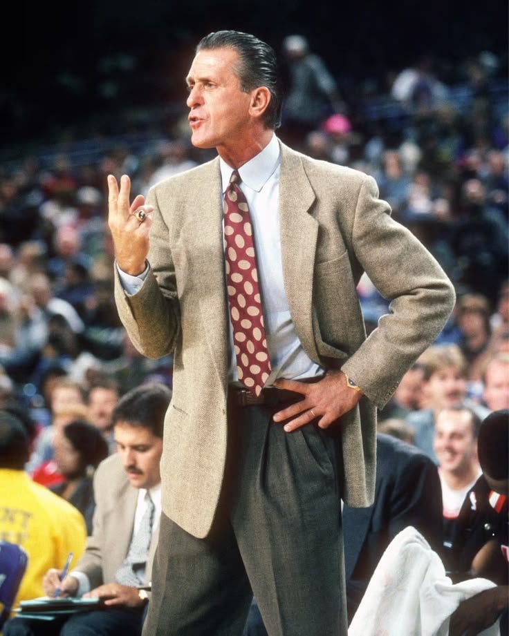This may contain: a man in a suit and tie standing on a basketball court